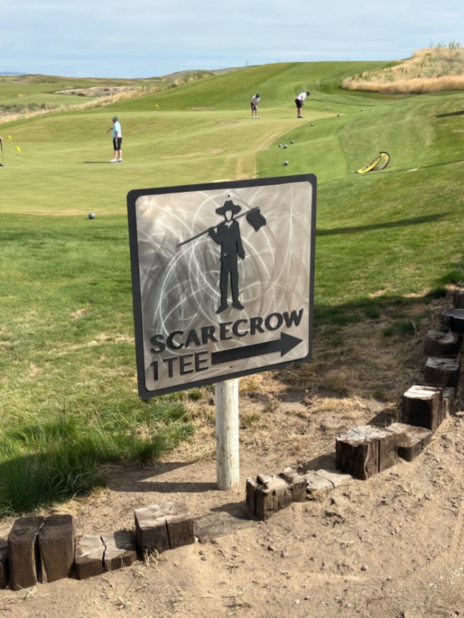 Scarecrow first tee sign with the putting green and rolling fescue hills at Gamble Sands, Brewster, Washington