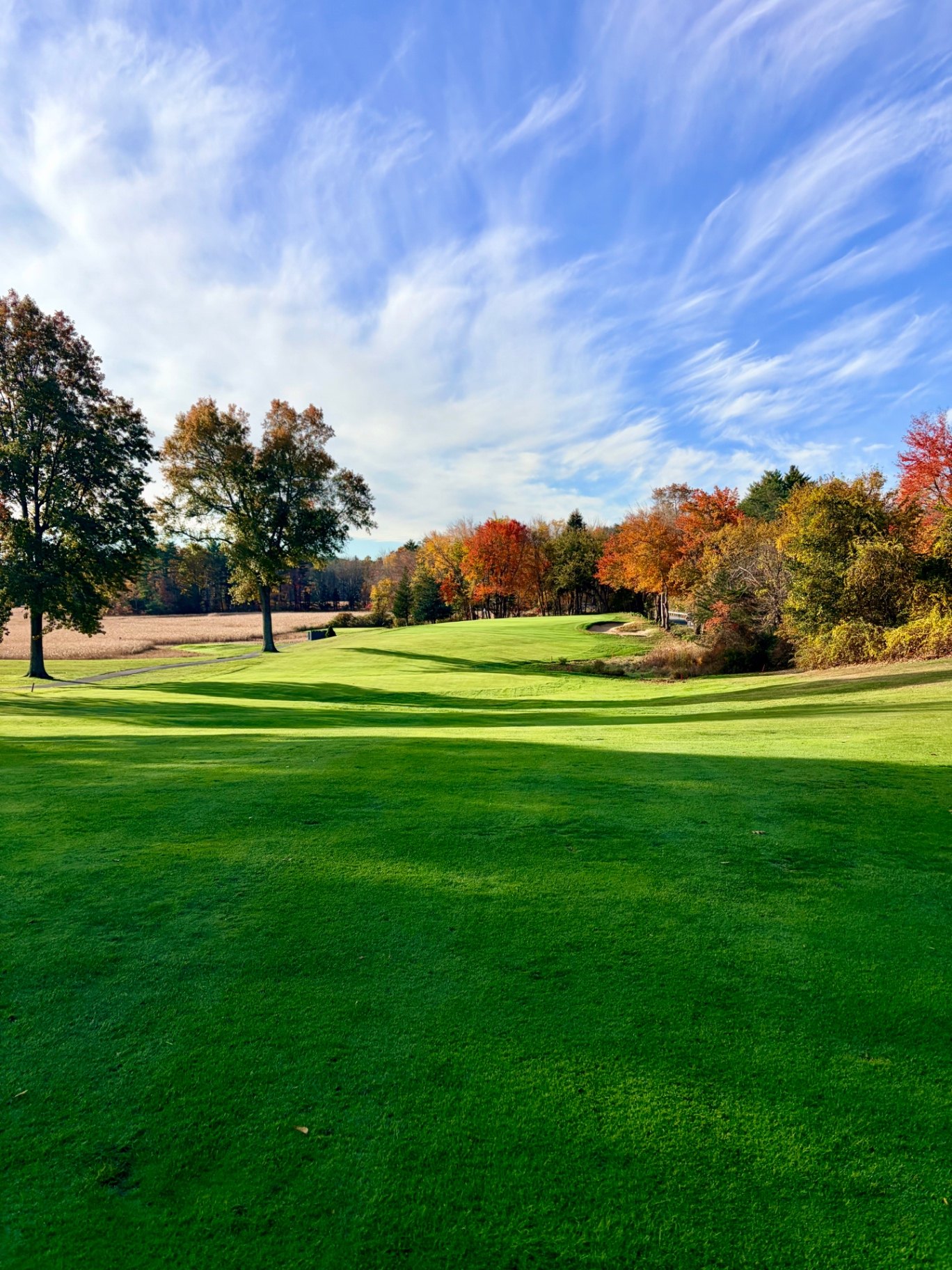 Fairway at Ould Newbury Golf Club framed by fall foliage under a blue sky