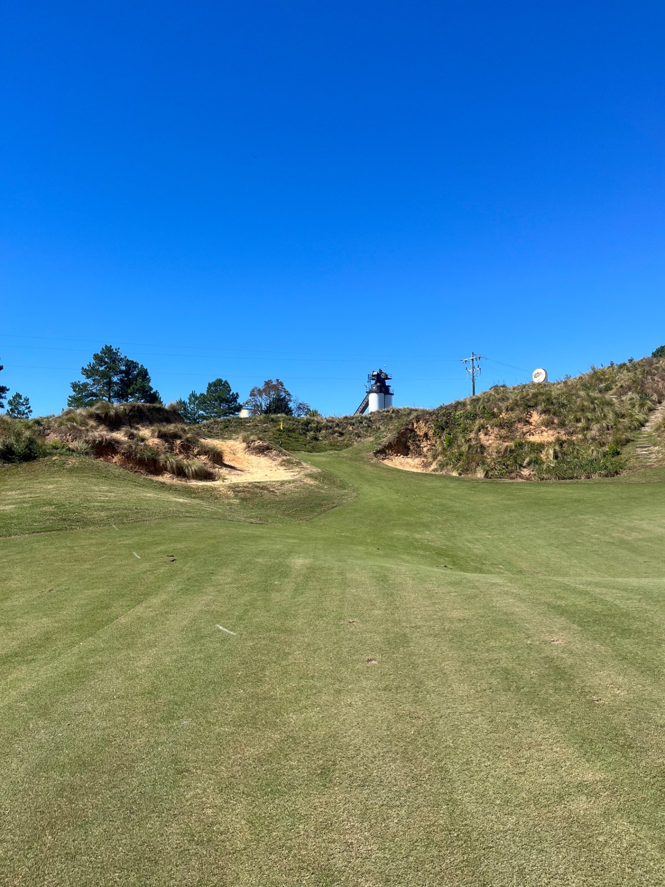 Narrow fairway framed by sandy bunkers and wiregrass-topped dunes at Tobacco Road Golf Club