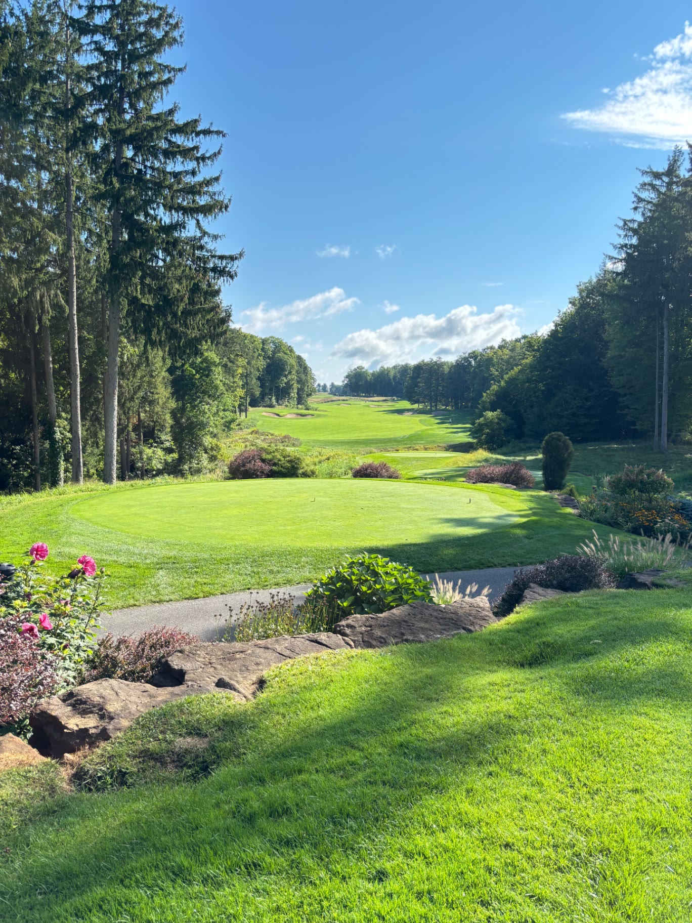 Par-3 green at Shenendoah Golf Club at Turning Stone framed by pines and flower beds