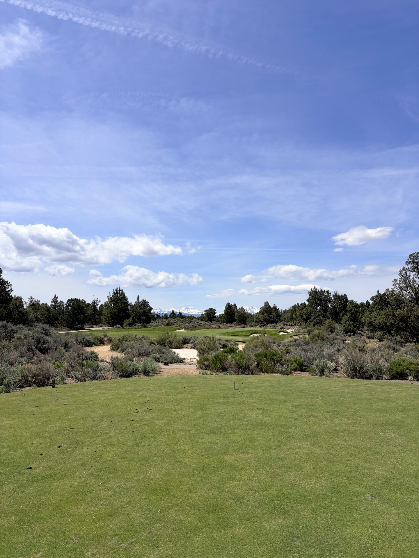 High-desert golf hole at Pronghorn Nicklaus Course with sage, sandy waste areas and Cascade peaks beyond