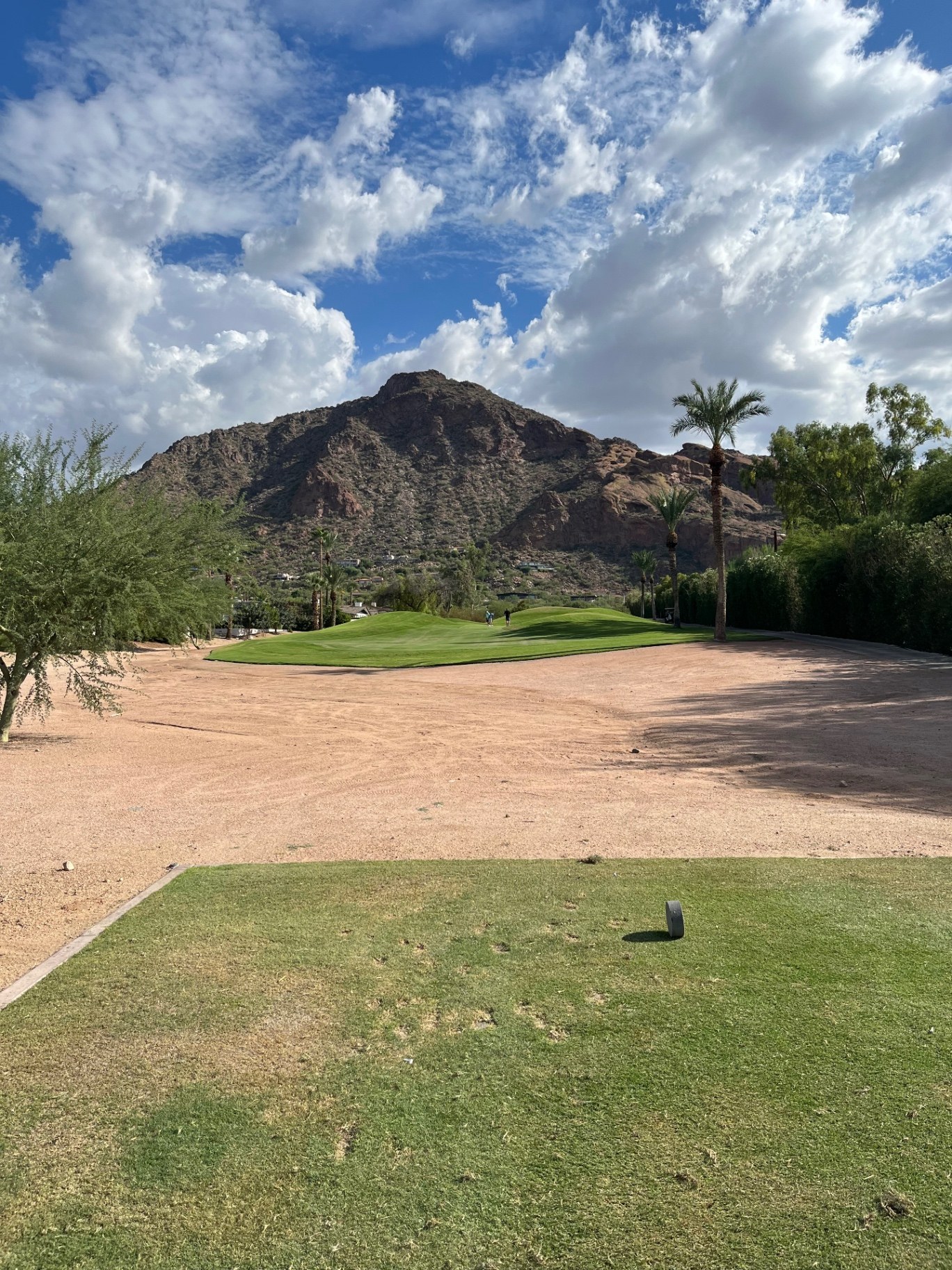 Tee view across desert sand toward a small green with palms and Camelback Mountain behind at The Short Course at Mountain Shadows