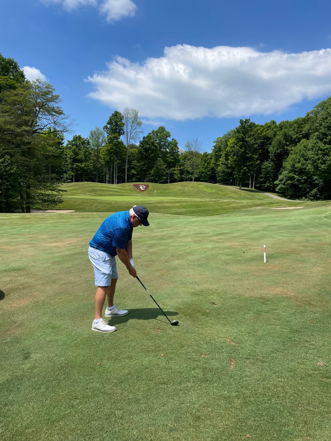 Golfer teeing off toward an elevated green framed by hardwood forest at Peek'n Peak Upper Course in Clymer, New York