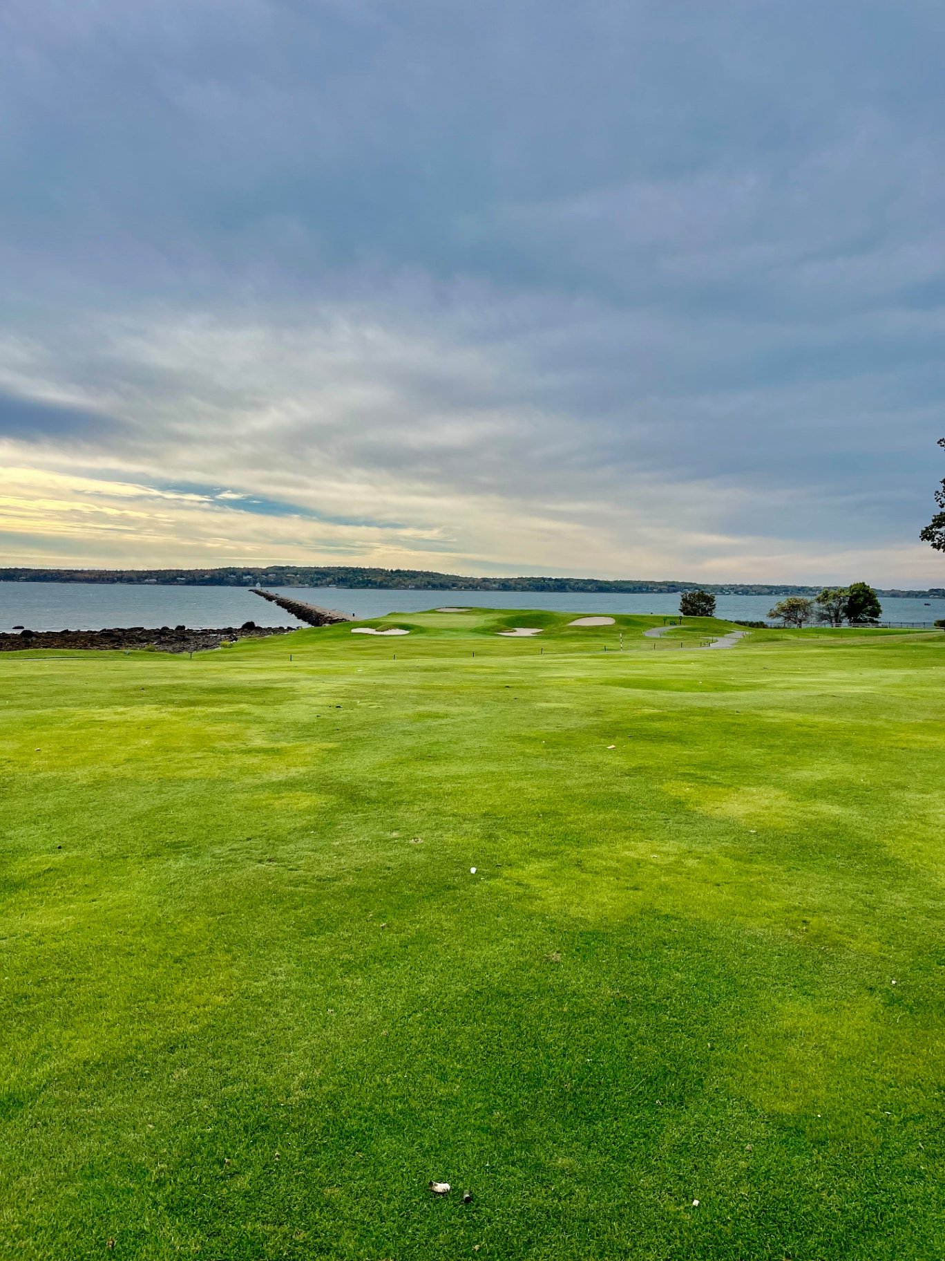 Oceanside green with bunkers and the Rockland Breakwater along Penobscot Bay at Samoset Resort Golf Course in Rockport, Maine