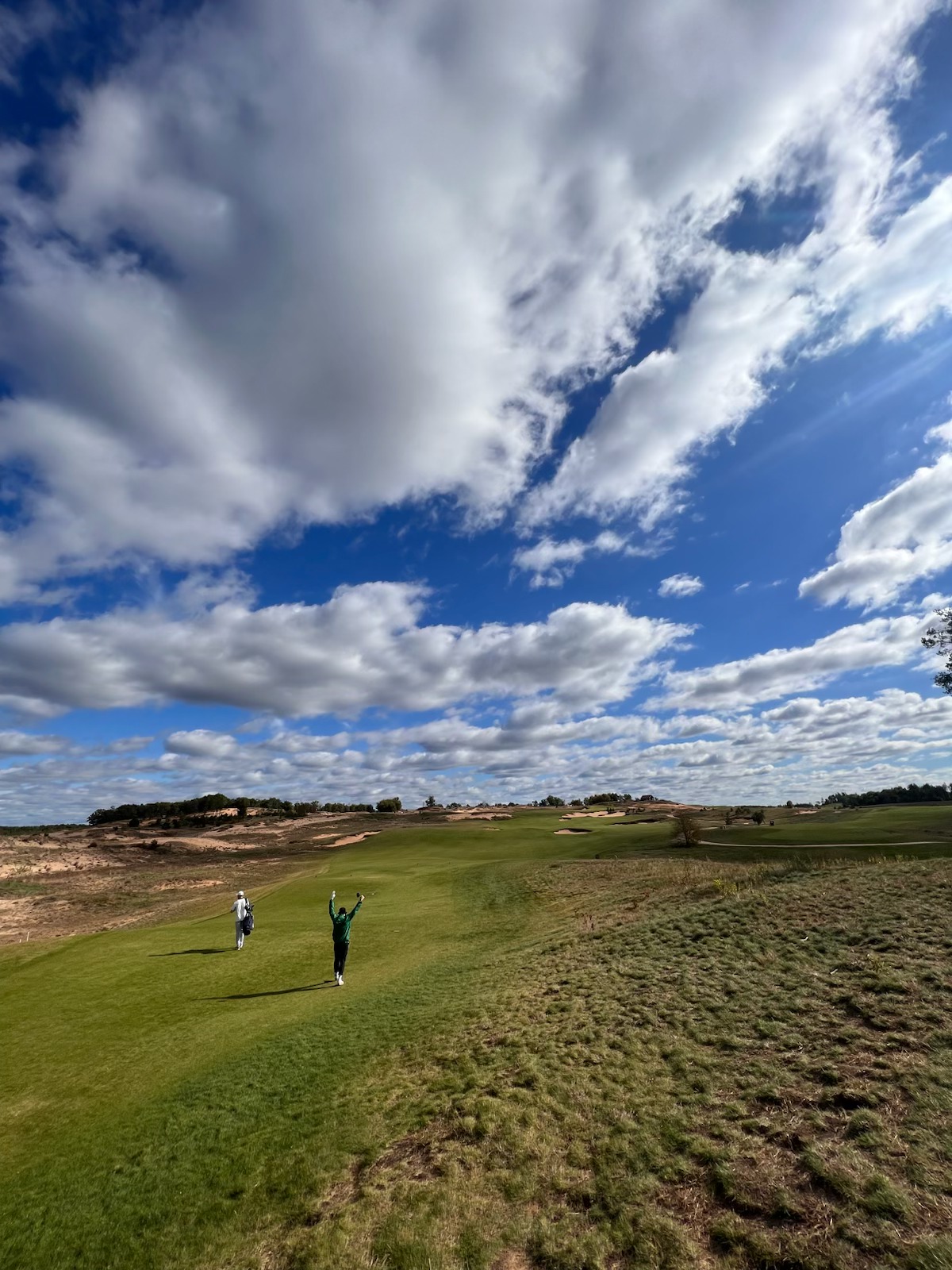 Golfers walking a wide sand-framed fairway under big prairie sky at Mammoth Dunes, Sand Valley Golf Resort in Nekoosa, Wisconsin