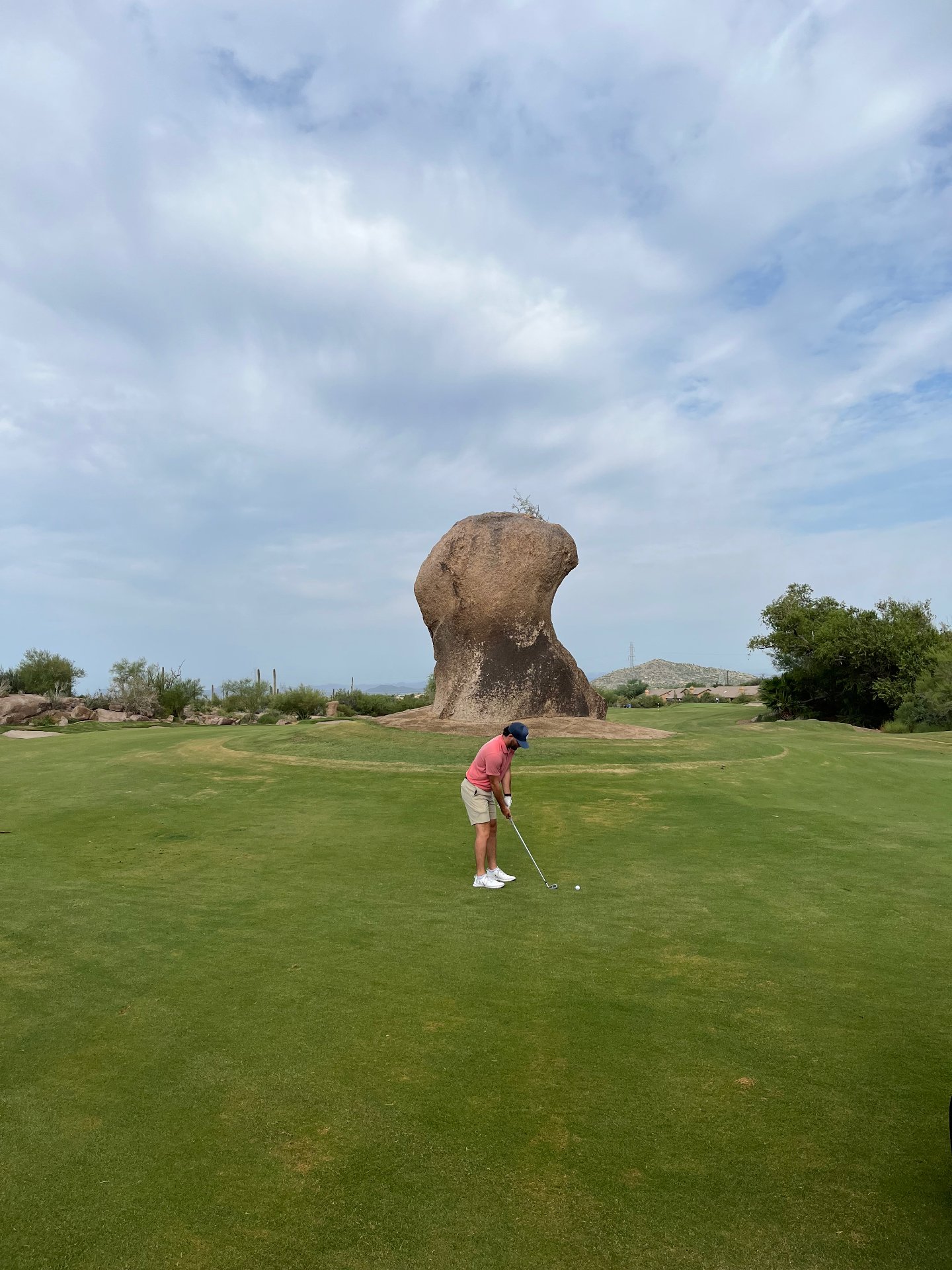 Golfer playing an approach shot past the giant granite boulder that gives the Monument course at Troon North its name, Scottsdale, Arizona
